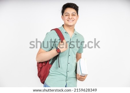 Portrait of happy indian teenager college or school boy with backpack holding books, isolated on white background. Smiling young asian male kid looking at camera. Royalty-Free Stock Photo #2159628349