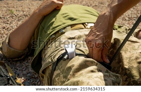 Army medics practice applying a tourniquet to the leg of a wounded soldier. Combat tactical equipment. Combat use Turnstile. The concept of military medicine. Royalty-Free Stock Photo #2159634315