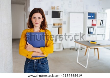 Young student stands in an office with her application documents and looks into the camera Royalty-Free Stock Photo #2159665419