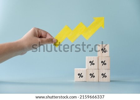 Yellow paper cut arrow going up positive trend on wooden blocks with percentages. Concept of profit increasing in percentage.