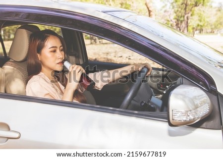 Asian woman drinking beer and alcoholic beverages while driving : Irresponsible women do not respect the law drink and drive risking accidents : Concept of not drinking, not driving for safety. Royalty-Free Stock Photo #2159677819