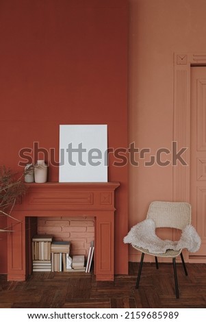 Elegant Scandinavian hygge style home living room interior. Cozy chair, fireplace, blank picture frame, red walls