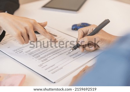Business car rental company service, hand of agent dealer is pointing to purchase contract of tenant to sign signature on document, new owner after signed rental , vehicle sales agreement.