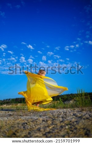 The symbol of freedom is a Ukrainian girl of 7 years old, patriotically dressed in a yellow dress against a blue sky. Blue sky. Sunny day. Free Ukrainian child. Child symbol of Ukraine