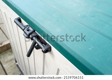 Large plastic weatherproof exterior storage chest used to store garden equipment. Showing detail of the locking system. Royalty-Free Stock Photo #2159706151