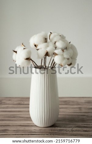 Cotton Sprigs with White Cotton Flowers in a Vase on a Wooden Surface.