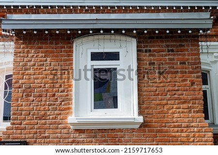 An old-style brick house, a window in the wall of the house, a white window, the facade of the building in Evprope, a historical landmark, roof lighting. High quality photo