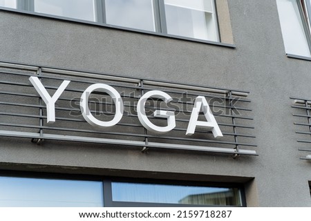 A building with a sign for yoga classes, yoga text hanging on the wall, a sign of a club of oriental practices, advertising on the street, white letters in the name of yoga. High quality photo