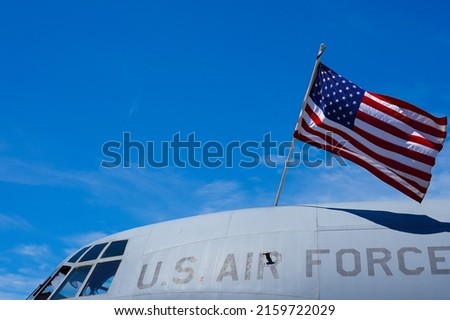The flag of America is hanging over a military airplane part of the US Air Force. Army industry in this difficult times of war. Royalty-Free Stock Photo #2159722029