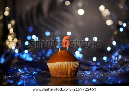 Digital gift card birthday concept. Tasty fresh homemade vanilla cupcake with number 16 sixteen on aluminium foil and blurred bright background in minimalistic style. High quality image