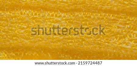 closeup, background, texture, large long horizontal banner. heterogeneous surface structure bright saturated yellow sponge for washing dishes, kitchen, bath. full depth of field. high resolution photo
