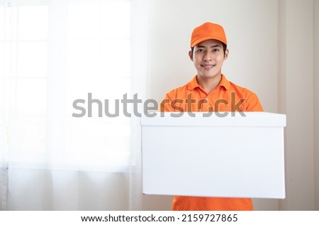 Young Asian caucasian delivery man in orange uniform with packages box and leadership in the modern office. Positive thinking and service mind. Banner cover