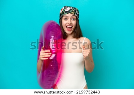 Young Ukrainian woman holding air mattress isolated on blue background celebrating a victory in winner position