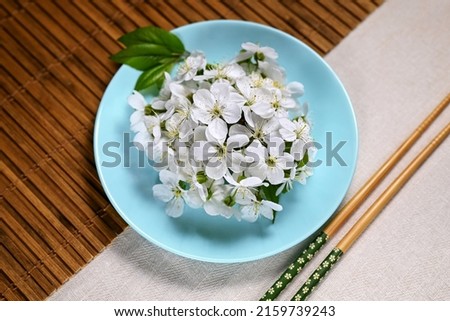 Spring composition. Round turquoise plate with white cherry flowers. Bamboo mat, chopsticks. Easy food concept, zero calorie.