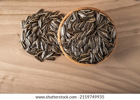 Black sunflower seeds in a bowl on wooden background