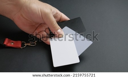 Hand of a man showing white, 18 percent gray and black color grading white balance cards. Close up