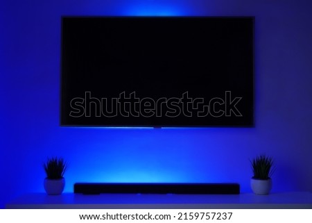 Blank BLACK TV screen in BLUE bright mockup, front view. Empty telly LED display in living room mock up. Clear panel monitor ready to use in powerpoint presentation. 