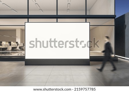 Businessman passing by blank white billboard with copyspace on sunny street before stylish business center with glass walls in the evening, mockup Royalty-Free Stock Photo #2159757785
