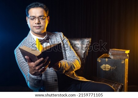 Male historian. Man is studying history books. Man reads old books. Dark-haired guy with textbook. Guy in plaid jacket. Man with book on dark background. Historian studying non-fiction Royalty-Free Stock Photo #2159771105