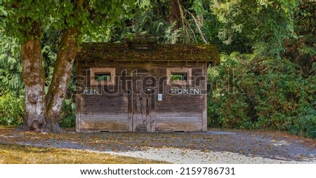 Outdoor toilet in nature for women and men in Canada. Wooden toilet room in the park. Street view, travel photo, selective focus
