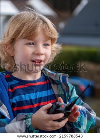 Blond boy communicates by radiotelephone outdoors Royalty-Free Stock Photo #2159788543