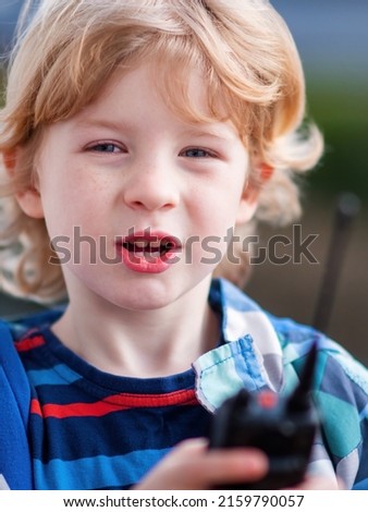 Blond boy communicates by radiotelephone outdoors Royalty-Free Stock Photo #2159790057