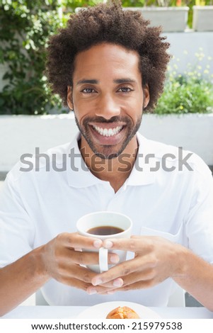 Smiling man having a coffee outside at the coffee shop