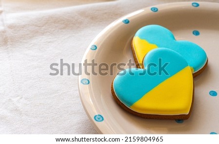 Plate with Two Heart shape ukrainian colours blue and yellow national flag gingerbread cookies on table, close up view
