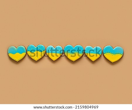 Heart shape ukrainian colours blue and yellow national flag gingerbread candies isolated on beige background.