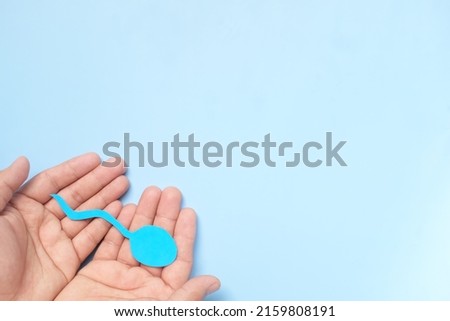 Top view of male hand holding sperm cutout in blue background. Men's health, sperm donation and care concept. Royalty-Free Stock Photo #2159808191