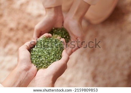 Hands of woman holding handful of nurdle, pre-production microplastic pellets