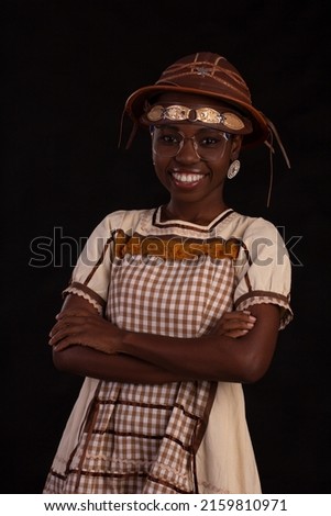 Young black woman wearing glasses and party dress with cancageiro hat and studio photo with black background. Festa Junina
