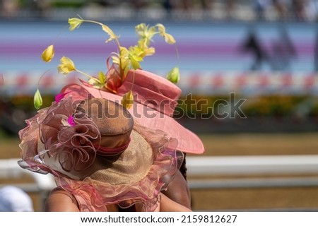 A couple of attendees at a horse race, wearing fancy hats. Royalty-Free Stock Photo #2159812627