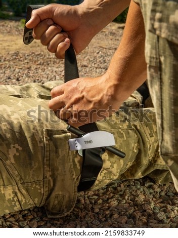 Army medics practice applying a tourniquet to the leg of a wounded soldier. Combat tactical equipment. Combat use Turnstile. The concept of military medicine. Royalty-Free Stock Photo #2159833749