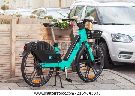 Bike Rent in City Street. Bicycle sharing service. Electric bike in urban environment.  Royalty-Free Stock Photo #2159843333