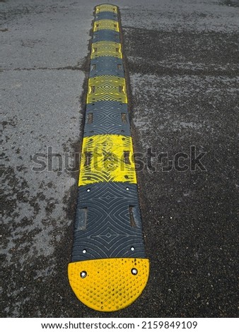 Used speed bump black with yellow stripes on the road to slow down the speed of the car, Concept to prevent accidents on the road.