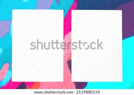 Colorful messy painted black, purple, teal urban wall texture with two wrinkled glued poster templates. Modern mockup for design presentation. Creative pink mint green blue urban city background. 
