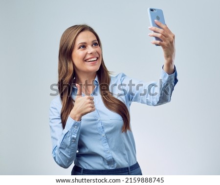 Smiling woman looking in smartphone and showing thumb up. isolated studio portrait.