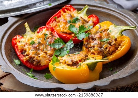 Stuffed peppers, halves of peppers stuffed with rice, dried tomatoes, herbs and cheese in a baking dish on a blue wooden table, top view.  (Turkish name; biber dolmasi) Royalty-Free Stock Photo #2159888967