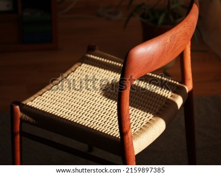 A danish mid century modern teak chair from the 60s vintage standing in the dining living room with paper cord seat teak wood 50s 70s retro original isolated on refurbished in living room closeup loft Royalty-Free Stock Photo #2159897385
