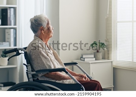 Lonely old senior Asian woman, sitting alone in the room, looking through the window Royalty-Free Stock Photo #2159904195