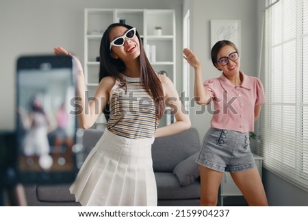 Asian young woman with her friend er created her dancing video by smartphone camera together To share video on social media application Royalty-Free Stock Photo #2159904237