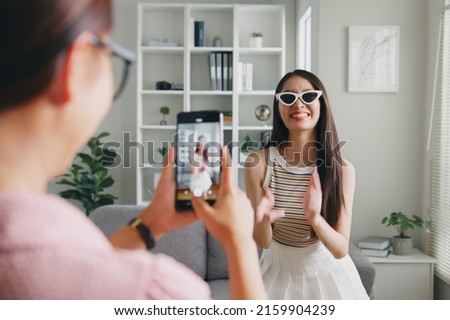 Asian young woman with her friend tiktoker created her dancing video by smartphone camera together. To share video on social media application  Royalty-Free Stock Photo #2159904239