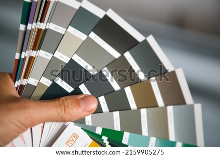 Selection of the paint color for decorative home repairs to the palette with layouts. A fan of shades in your hand inside the home. Repair and construction, paint and varnish coating