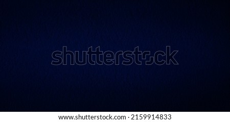 Black background with spotlight. The background image of the dark colored concrete wall has light from the top of the picture. There is space for designing and inserting advertisements.