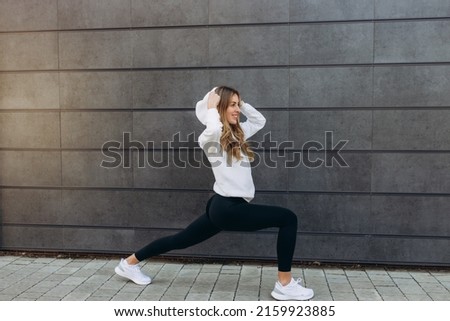 Portrait sporty girl doing stretching exercise over gray wall background