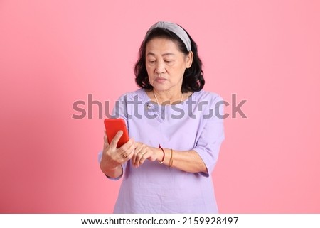 The senior Asian woman with brown dressed standing on the Pink background.
