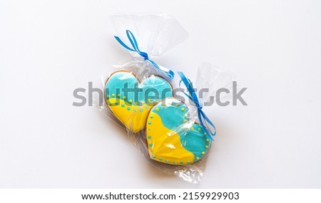 Two Heart shape ukrainian colours blue and yellow national flag gingerbread candies in a transparent cellophane on white background.