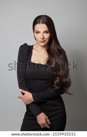 Fashion beauty portrait of a beautiful young brunette woman with long wavy hair wearing black cocktail dress posing Royalty-Free Stock Photo #2159933515