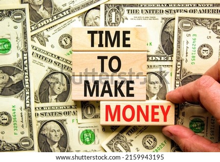 Time to make money symbol. Concept words Time to make money on wooden blocks on a beautiful background from dollar bills. Businessman hand. Business, finacial and time to make money concept.